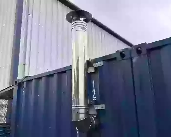 Vertical stainless steel chimney installed on container housing a Nilfisk Truck Booster to safely vent boiler exhaust in Lichfield.